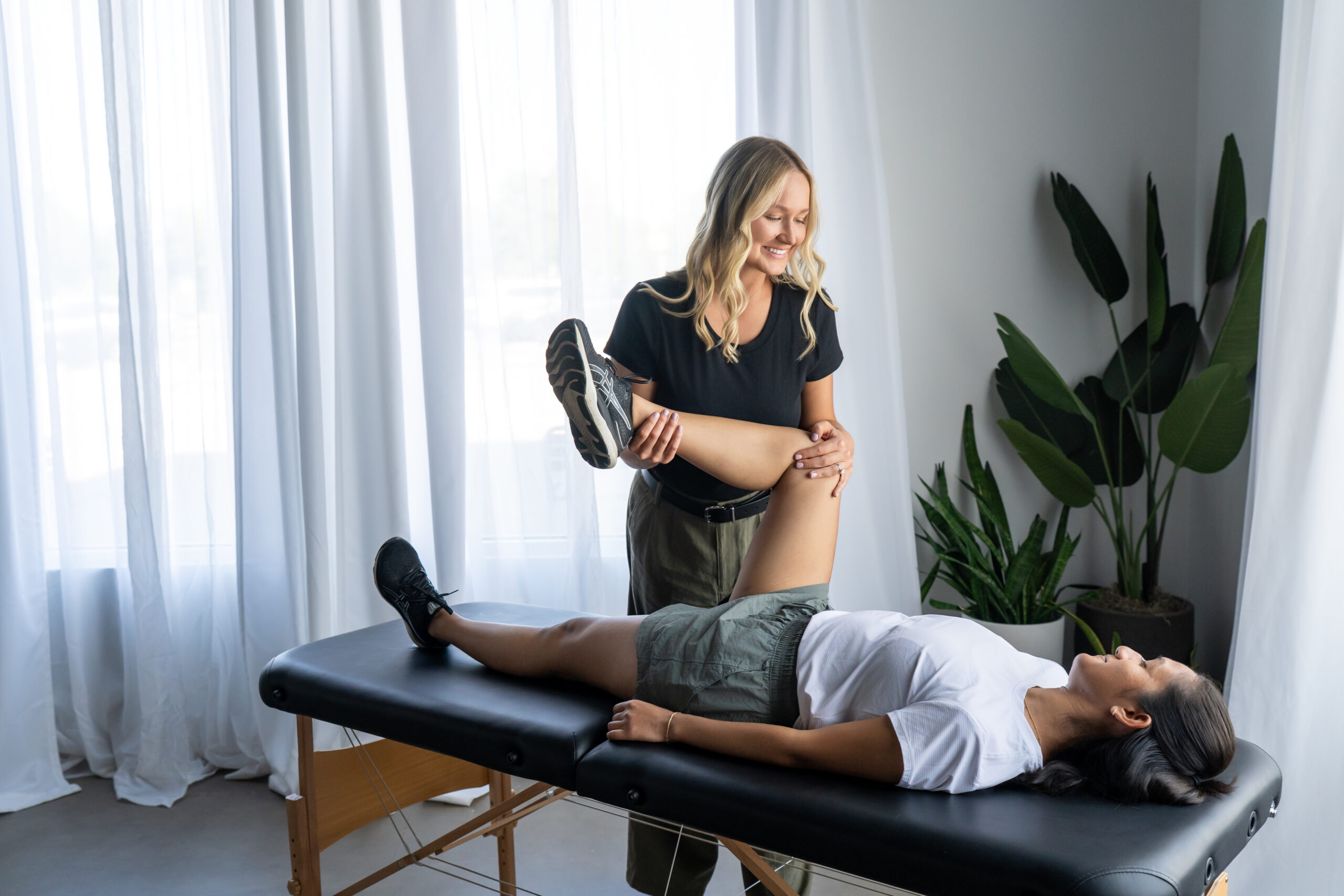 Pelvic floor physical therapist guiding a pregnant woman through hip mobility exercises in clinic